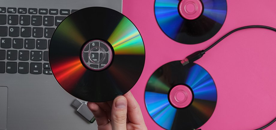 Female hand holds cd drives against the background of gadgets